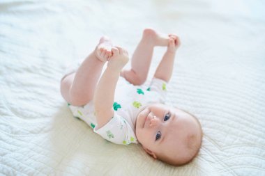 Sırtüstü yatıp ayaklarına dokunan tatlı bir kız çocuğu. Mutlu sağlıklı çocuk evde, kreşte.