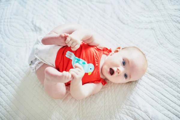 Linda Niña Acostada Boca Arriba Tocando Sus Pies Feliz Niño — Foto de Stock