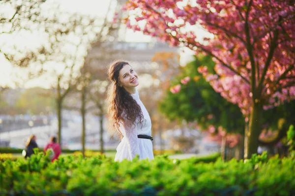 フランスのパリで桜の季節を楽しんでいる白いドレスで幸せな若い女 — ストック写真