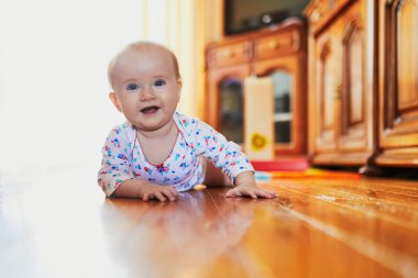 Bebek emeklemeyi öğreniyor. Yerde mutlu, sağlıklı bir çocuk var. Evde küçük bir çocuk var.