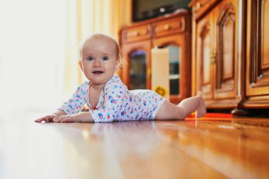 Bebek emeklemeyi öğreniyor. Yerde mutlu, sağlıklı bir çocuk var. Evde küçük bir çocuk var.
