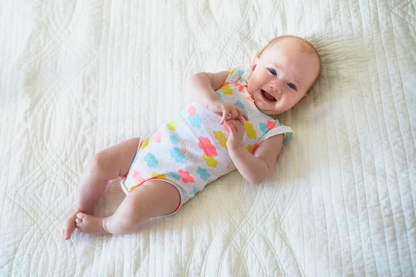 可爱的女婴躺在床上笑着 快乐健康的小孩笑了 在阳光灿烂的托儿所里的婴儿 — 图库照片