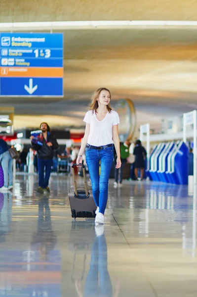 年轻女子在国际机场走带着行李 准备她的航班 — 图库照片