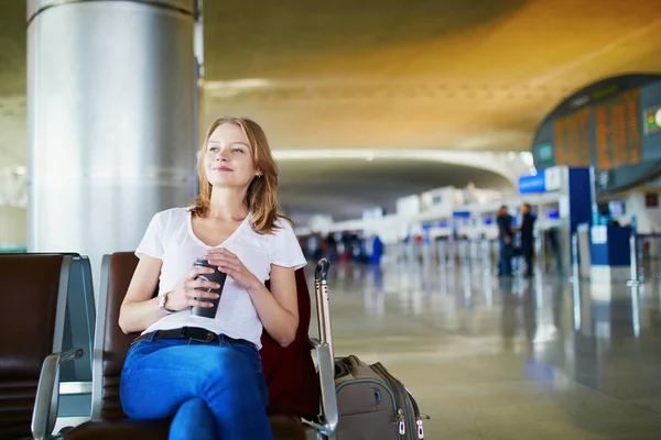 年轻女子在国际机场携带行李和咖啡去 等待她的航班 — 图库照片