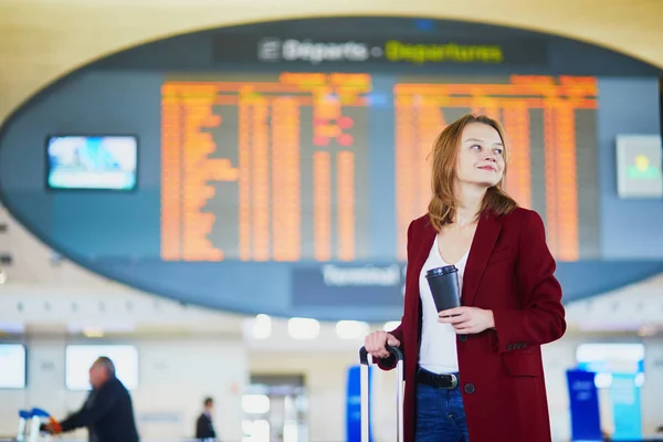 年轻女子在国际机场携带行李和咖啡去等待她的航班 — 图库照片