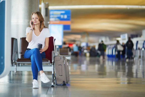 国际机场的年轻女子带着行李和咖啡走 等着航班 通电话 — 图库照片