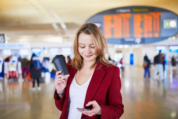 彼女のフライトを待って行くに荷物とコーヒーの国際空港で若い女性 — ストック写真