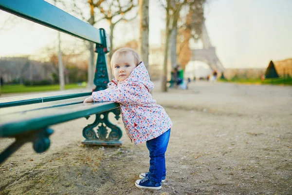 エッフェル塔の近くのベンチの横に立っている1歳の少女 幼児は歩く方法を学ぶ フランス 子供と一緒に旅行する — ストック写真