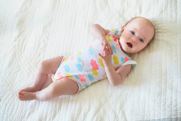 Babymeisje liggend op bed en glimlachen — Stockfoto