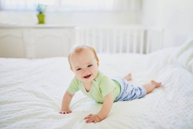 Bebek yatakta emekliyor ve gülüyor.