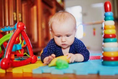 Bebek kız yerde oyuncaklarla oynuyor.