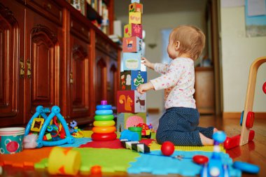 Bebek kız yerde oyuncaklarla oynuyor.