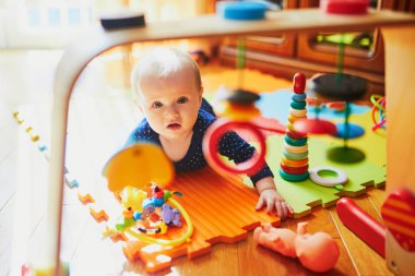 Bebek kız yerde oyuncaklarla oynuyor.