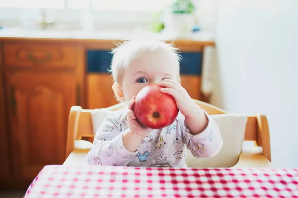 Cute baby girl jedzenia jabłka w kuchni — Zdjęcie stockowe