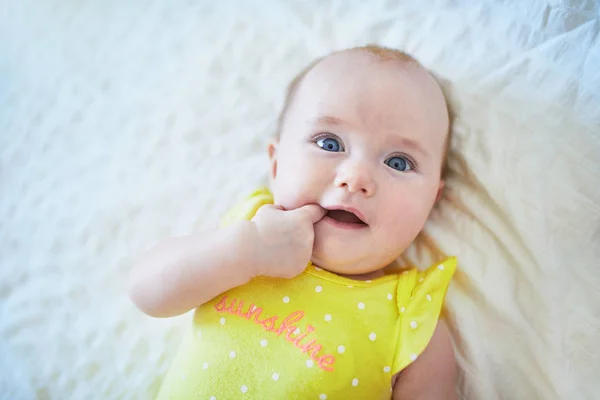 Porträtt av söt liten flicka som ligger på rygg på sängen och suger sitt finger — Stockfoto
