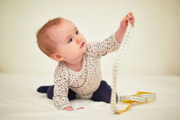 Cute little girl playing with centimeter tape measure