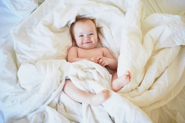 Söt liten flicka som leker i sängen — Stockfoto