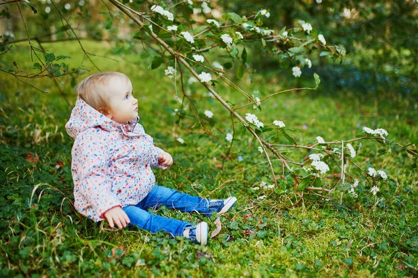 One year old girl sitting on the grass under tree branch — Stock fotografie