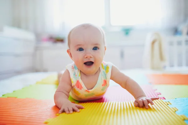 Baby meisje liggend op kleurrijke speelmat op de vloer — Stockfoto
