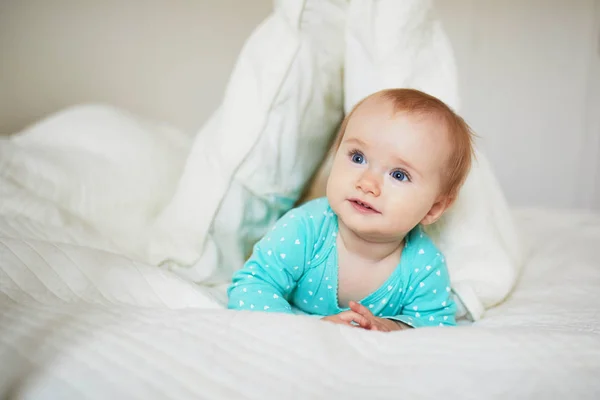 Roztomilá holčička hrající si s polštáři na posteli — Stock fotografie