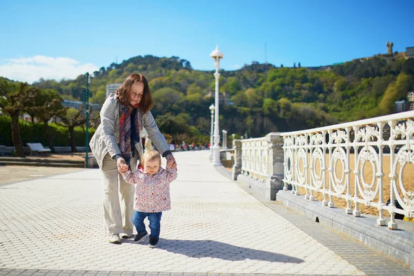 Grandmother helping granddaughter make her firts steps — Stock Photo, Image