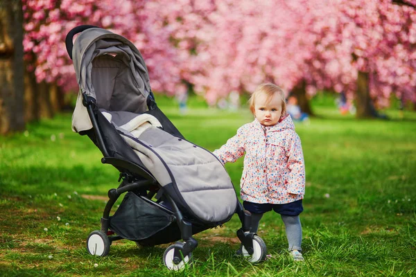 Jeden rok stary dziewczyna stojący obok jej wózek w Park — Zdjęcie stockowe