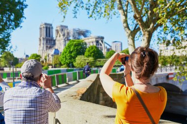 Çatısı ve kulesi olmadan Notre Dame katedralinin fotoğraflarını çeken insanlar