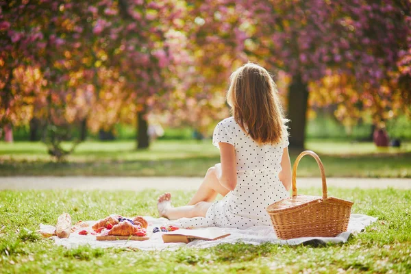 Güneşli bahar gününde parkta piknik yapan bir kadın. Kiraz çiçeği mevsiminde. — Stok fotoğraf