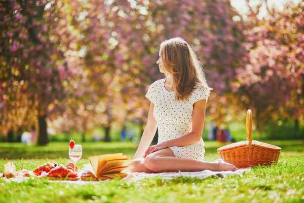 Güneşli bahar gününde parkta piknik yapan bir kadın. Kiraz çiçeği mevsiminde. — Stok fotoğraf