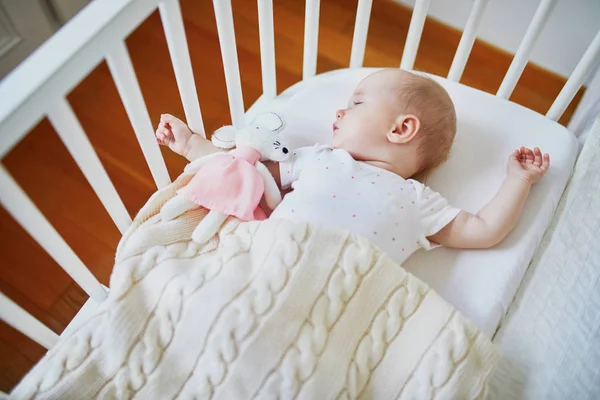 Baby sleeping in co-sleeper crib attached to parents 'bed — стоковое фото