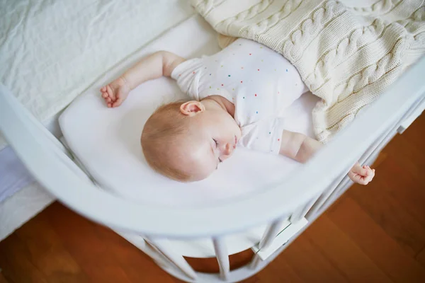 Baby sleeping in co-sleeper crib attached to parents 'bed — стоковое фото