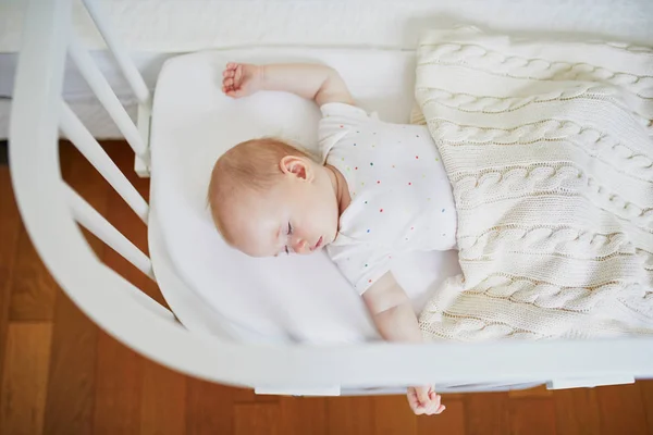 Baby sleeping in co-sleeper crib attached to parents\' bed