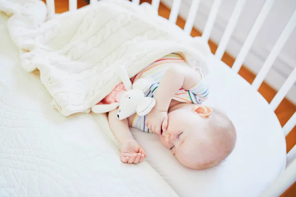 Baby sleeping in co-sleeper crib attached to parents 'bed — стоковое фото