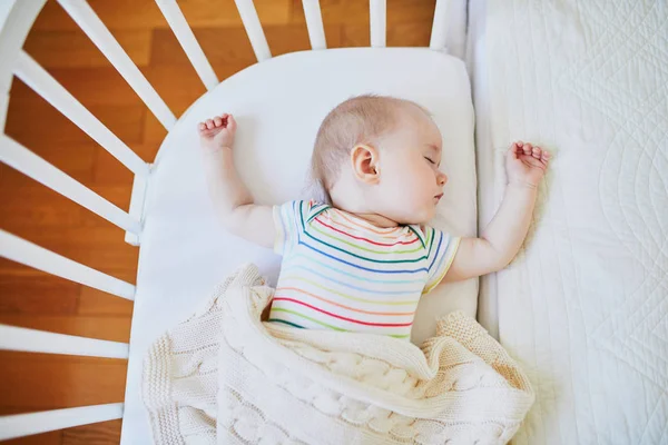 Baby sleeping in co-sleeper crib attached to parents 'bed — стоковое фото