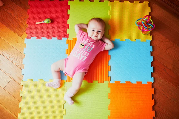 カラフルなプレイマットの上に横たわっている4ヶ月の女の赤ちゃん — ストック写真