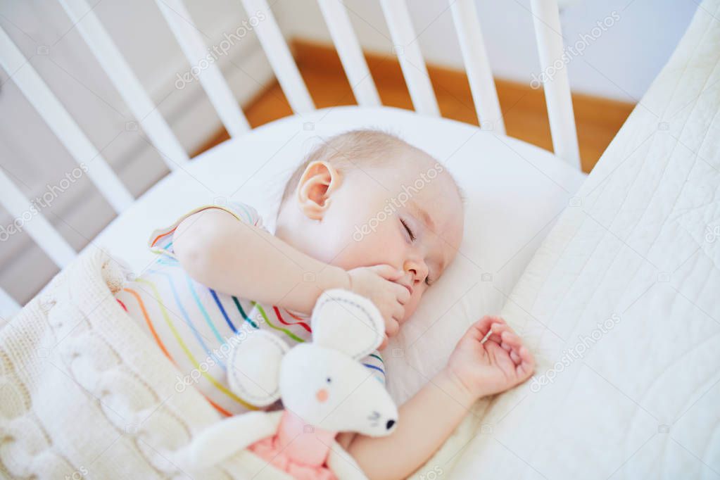 Baby sleeping in co-sleeper crib attached to parents' bed