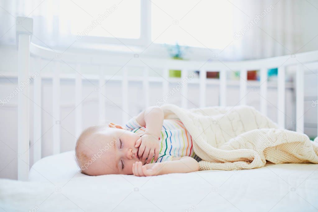 Baby sleeping in co-sleeper crib attached to parents' bed