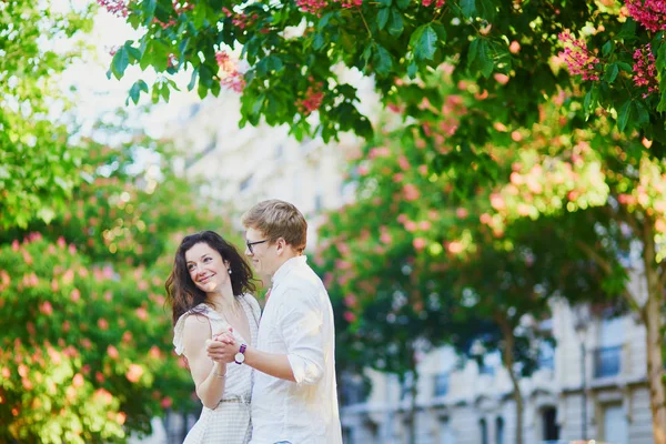 Glückliches romantisches Paar in Paris, das sich unter rosa Kastanien in voller Blüte umarmt — Stockfoto