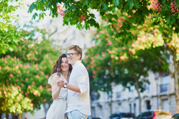 Lyckligt romantiskt par i Paris, kramar under rosa kastanjer i full blom — Stockfoto