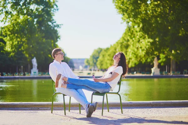 Šťastný romantický pár v Paříži, který sedí na tradičních zelených kovových křeslech v Tuileriích zahrádce — Stock fotografie