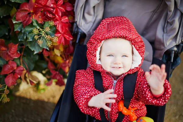 Girl in bright stylish clothes sitting in pushchair outdoors on a fall day — Stock Photo, Image