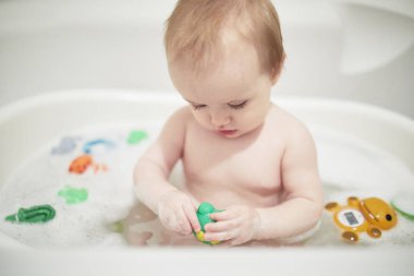 Küçük küvette lastik oyuncaklarla oynayan sevimli küçük kız.