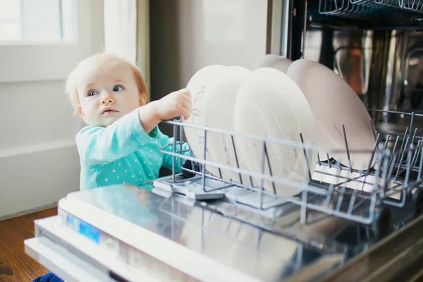 Małe dziecko pomaga rozładować zmywarkę — Zdjęcie stockowe