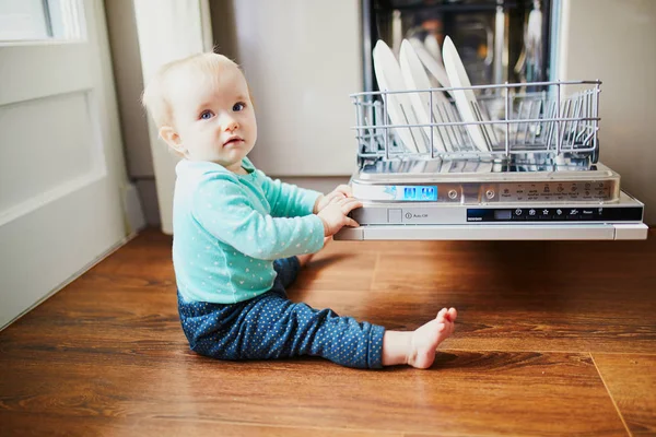 Маленька дитина допомагає розвантажити посудомийну машину — стокове фото