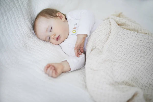 Adorável bebê menina dormindo no berço sob cobertor de malha — Fotografia de Stock