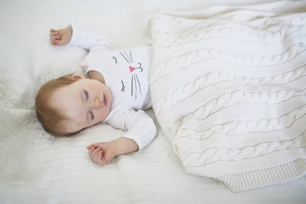 Adorable baby girl sleeping in crib under knitted blanket — Stock Photo, Image