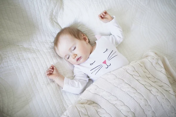 Adorável bebê menina dormindo no berço sob cobertor de malha — Fotografia de Stock