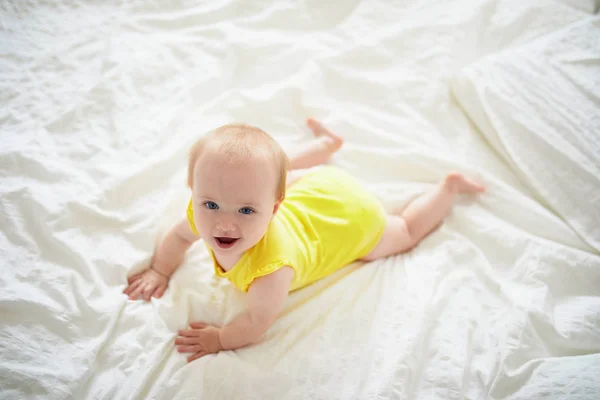 Bebé niña arrastrándose en la cama y riendo — Foto de Stock