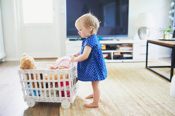 Очаровательная девочка в синем платье играет с игрушками — стоковое фото