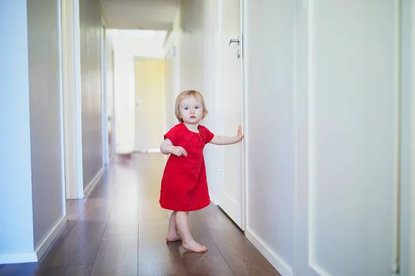 Niña en vestido rojo de pie cerca de la pared — Foto de Stock